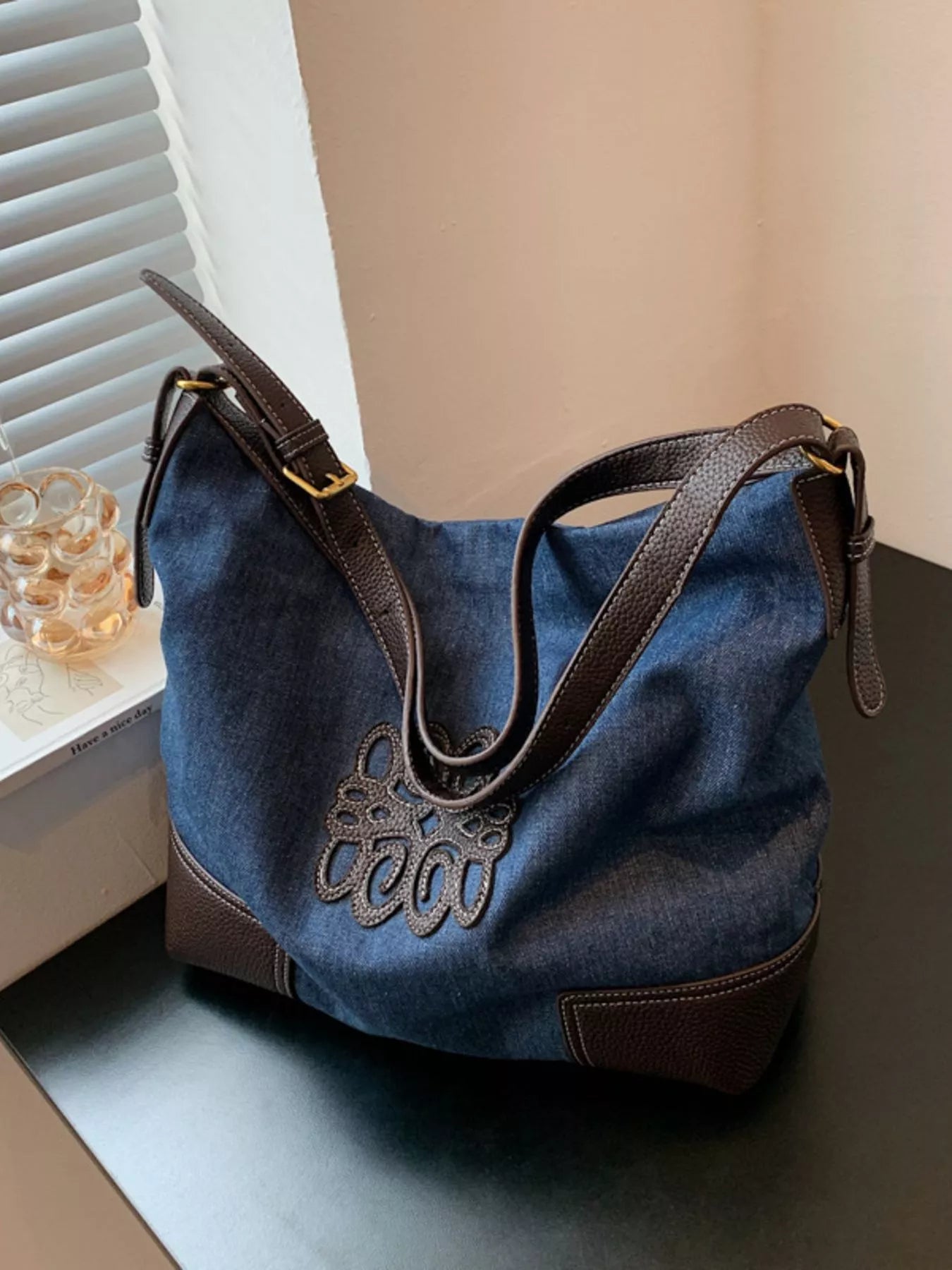 Blue denim shopper bag with brown trim and embroidered detail