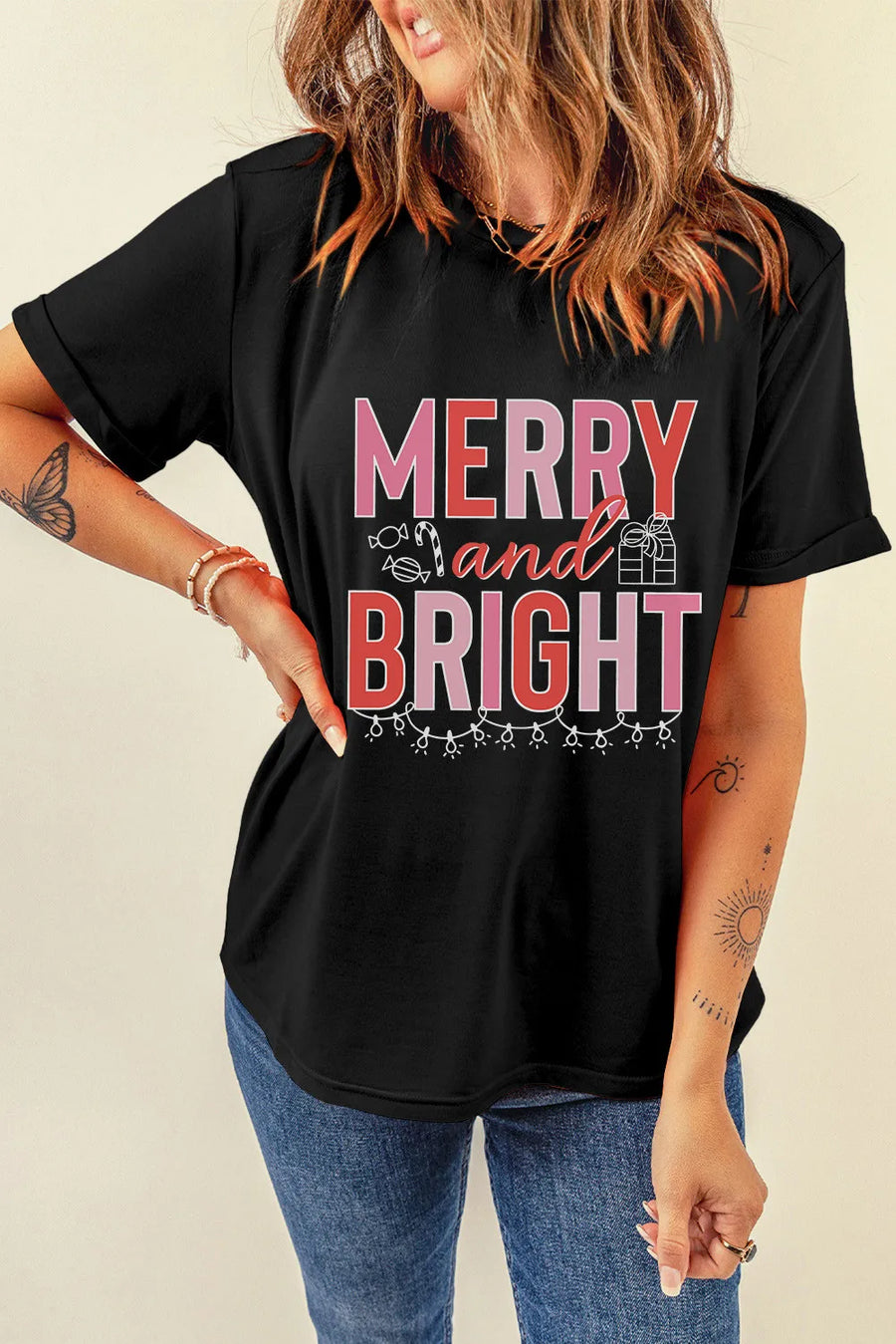 Black cotton tee with rolled sleeves and "Merry and Bright" graphic featuring holiday icons.