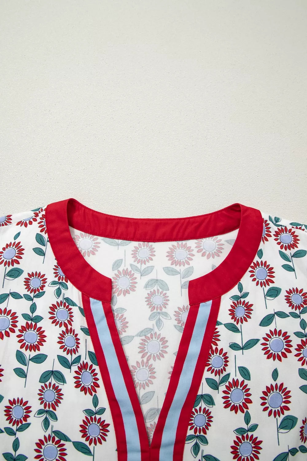 Vibrant floral midi dress with red trim, blue and red striped V-neck detail.