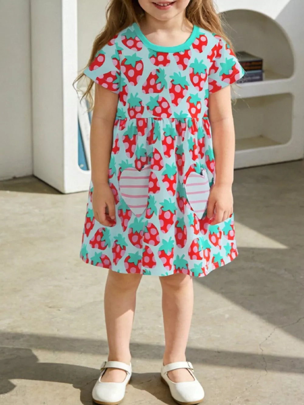 Toddler girls' light blue cotton dress with red strawberry print and pink striped heart pockets.