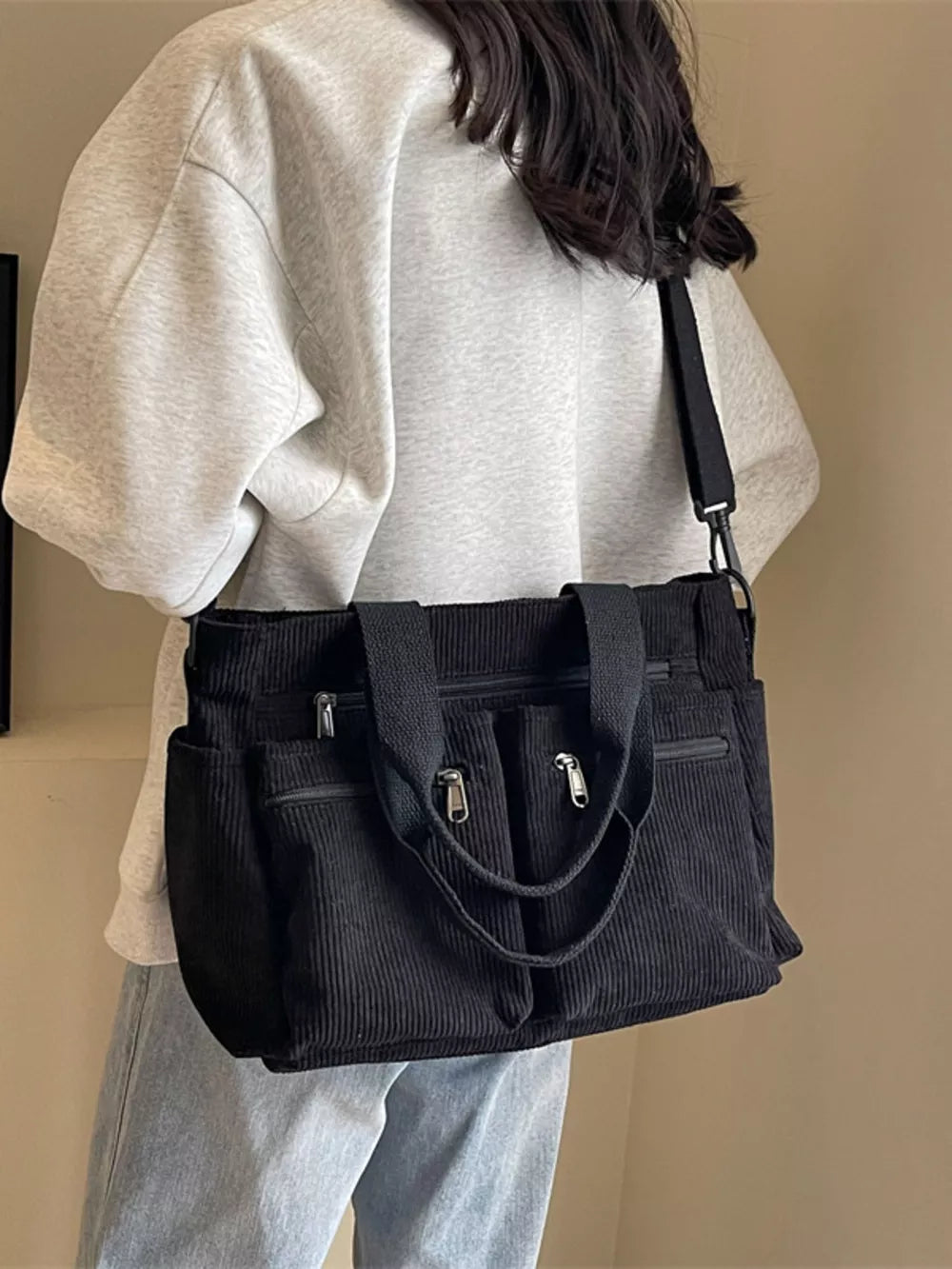 Textured black corduroy crossbody bag with multiple zippered pockets and adjustable strap.