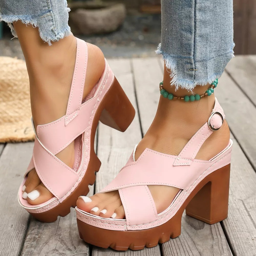 Pink open toe block heel sandals with cross straps and chunky sole.