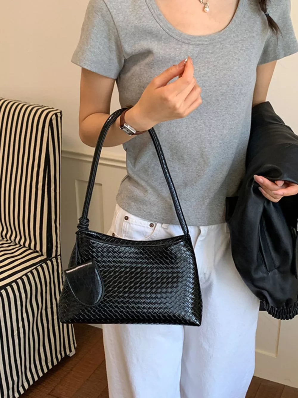 Black shoulder bag featuring woven texture and geometric