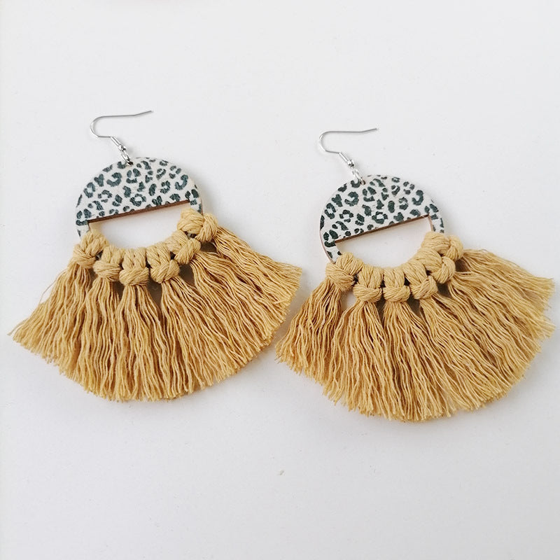 Leopard print tassel earrings with mustard yellow fringe and wooden half-circle detail.