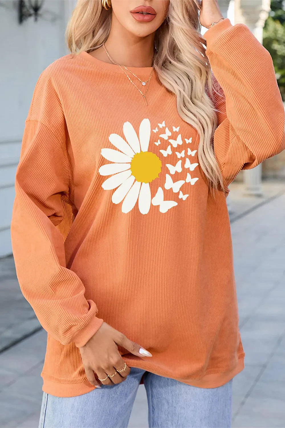 Daisy graphic corduroy crewneck sweatshirt in sherbet with a yellow daisy and white butterflies.