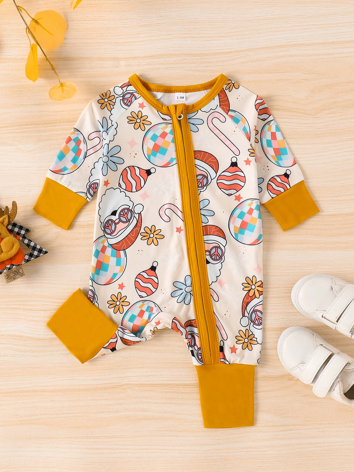 Baby one-piece with holiday disco ball, candy cane, and Santa print, yellow trim, long sleeves.