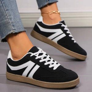 Retro black suede sneakers with white chevron detail and white laces.