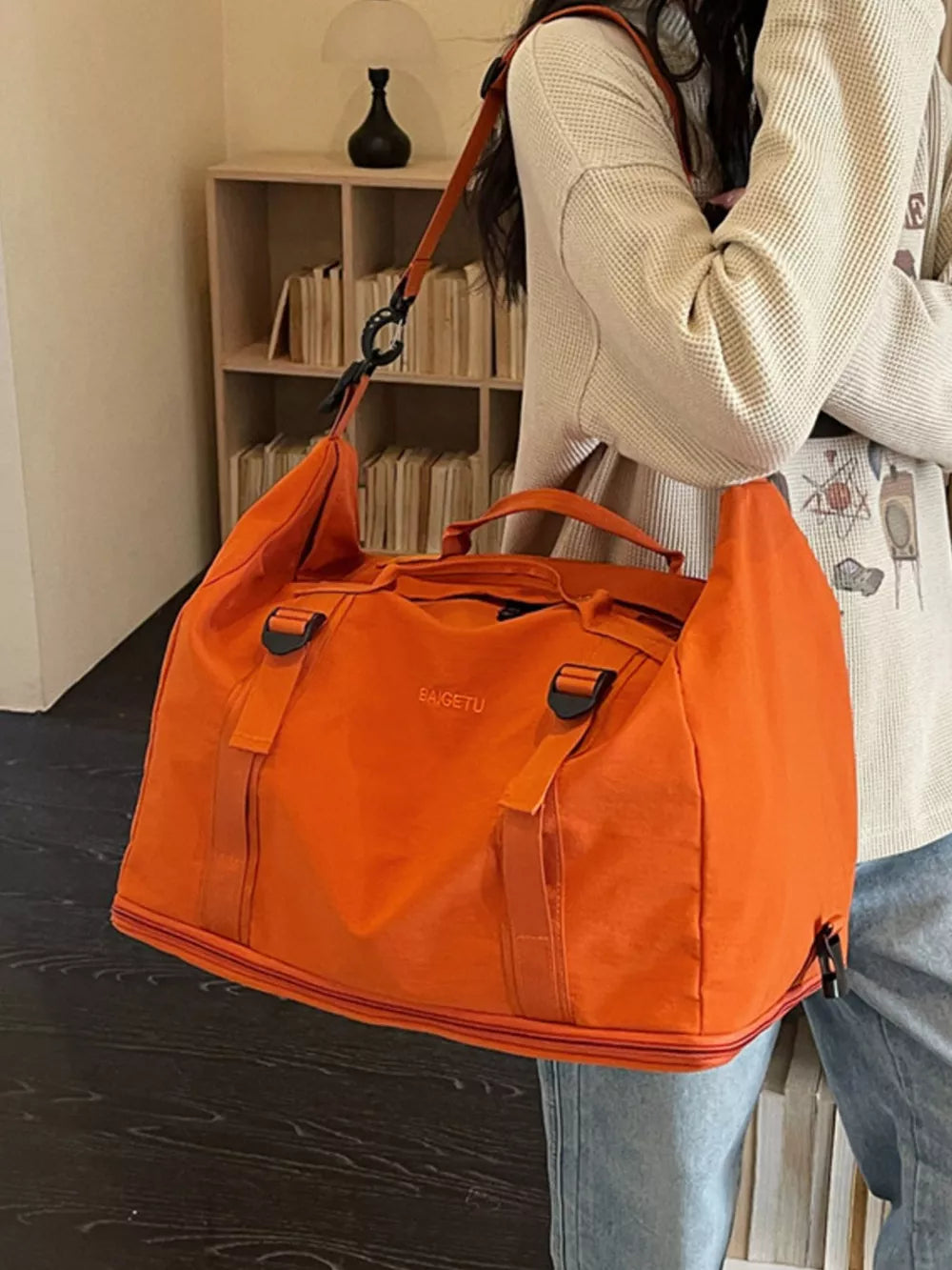 Orange nylon travel bag with buckle straps and crinkled texture.
