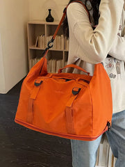 Orange nylon travel bag with buckle straps and crinkled texture.