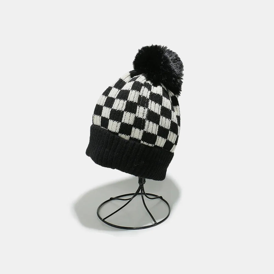 Checkerboard knit beanie with black faux fur pom and ribbed band.