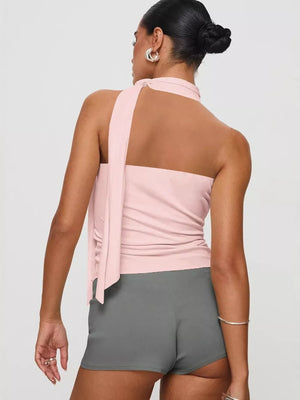 Pink halter top with draped tie detail and ruched sides, paired with grey shorts.