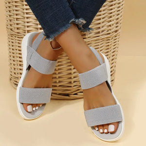 Sporty knit strap sandals in dark gray with white soles and elastic bands.