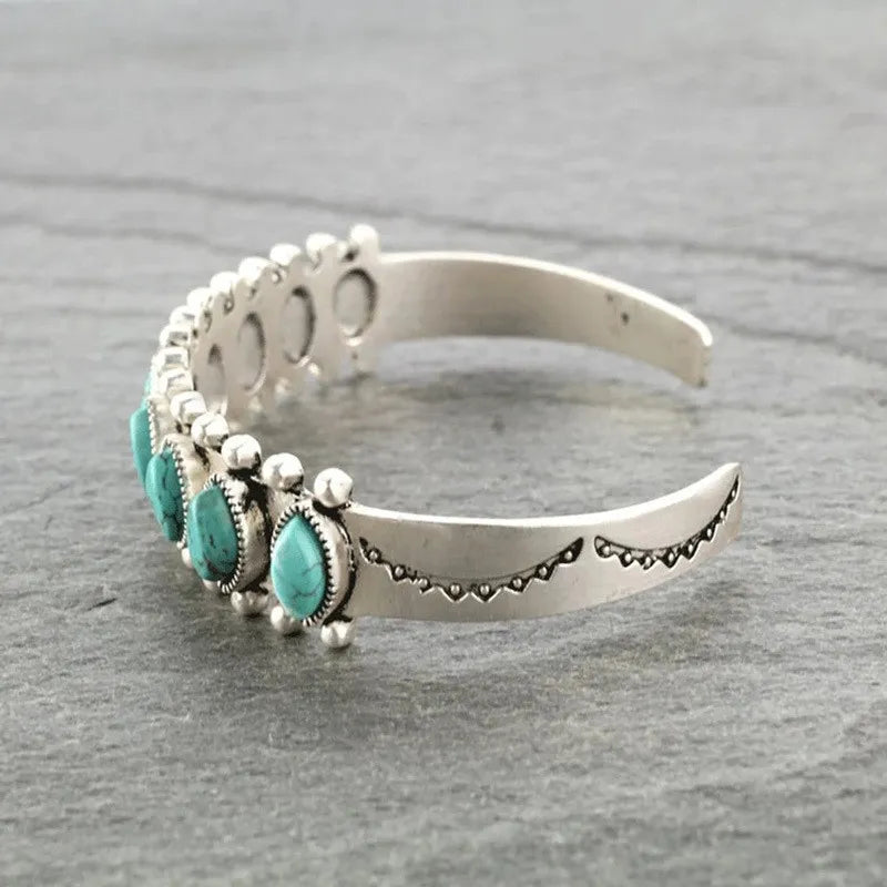 Turquoise cabochon open bangle bracelet with silver alloy and decorative etching.
