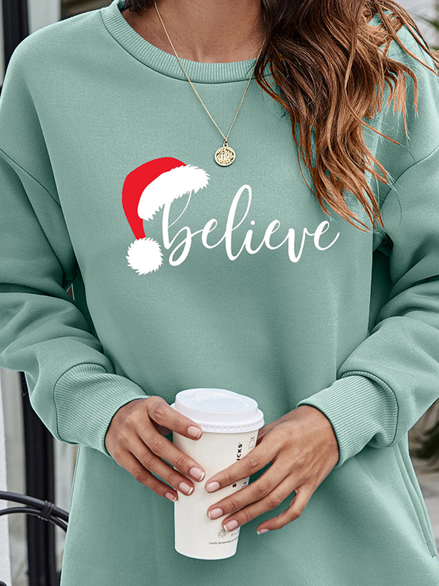 Sage Christmas graphic tunic sweatshirt with Santa hat and "believe" text.