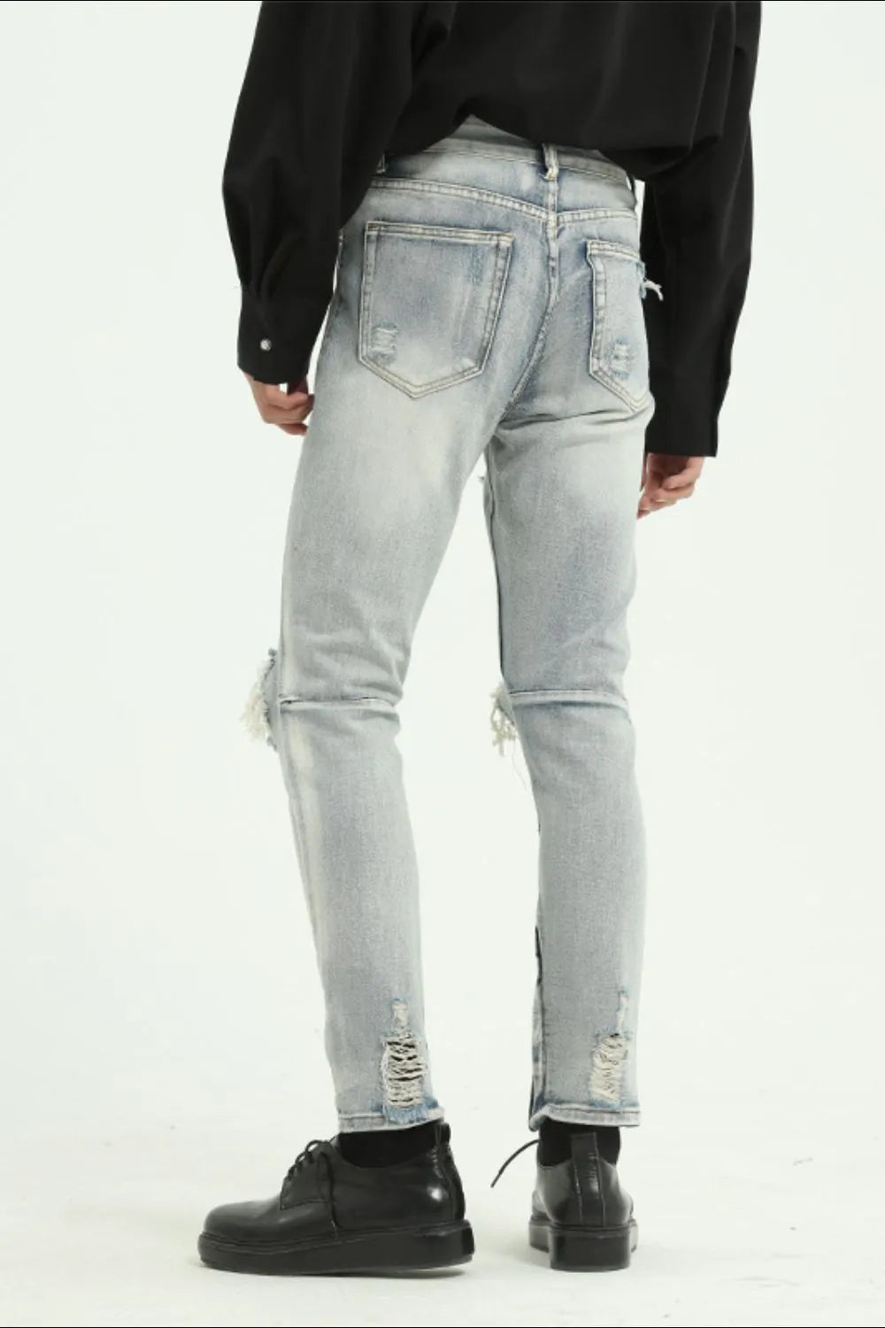 Light wash distressed skinny jeans with ankle zippers and ripped details.