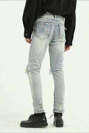 Light wash distressed skinny jeans with ankle zippers and ripped details.