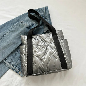 Padded silver nylon tote bag with exterior pockets and black straps