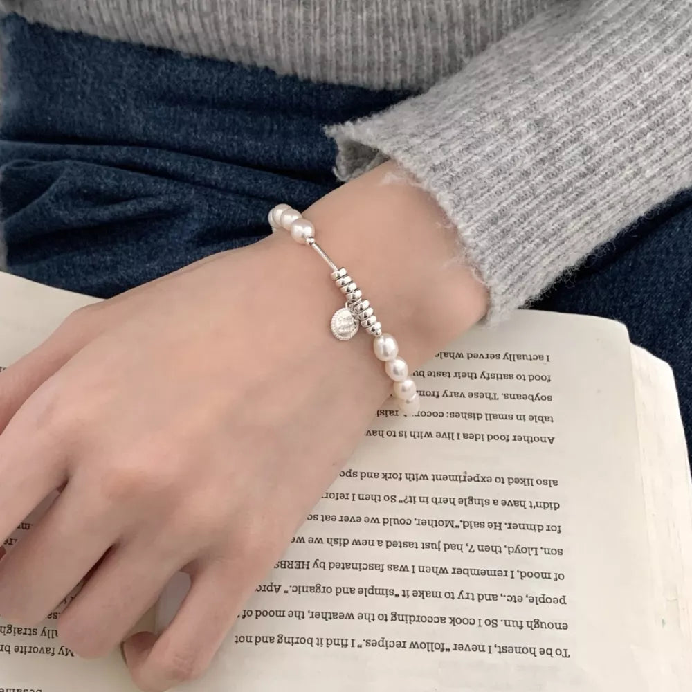 Delicate freshwater pearl and silver bracelet with charm detail