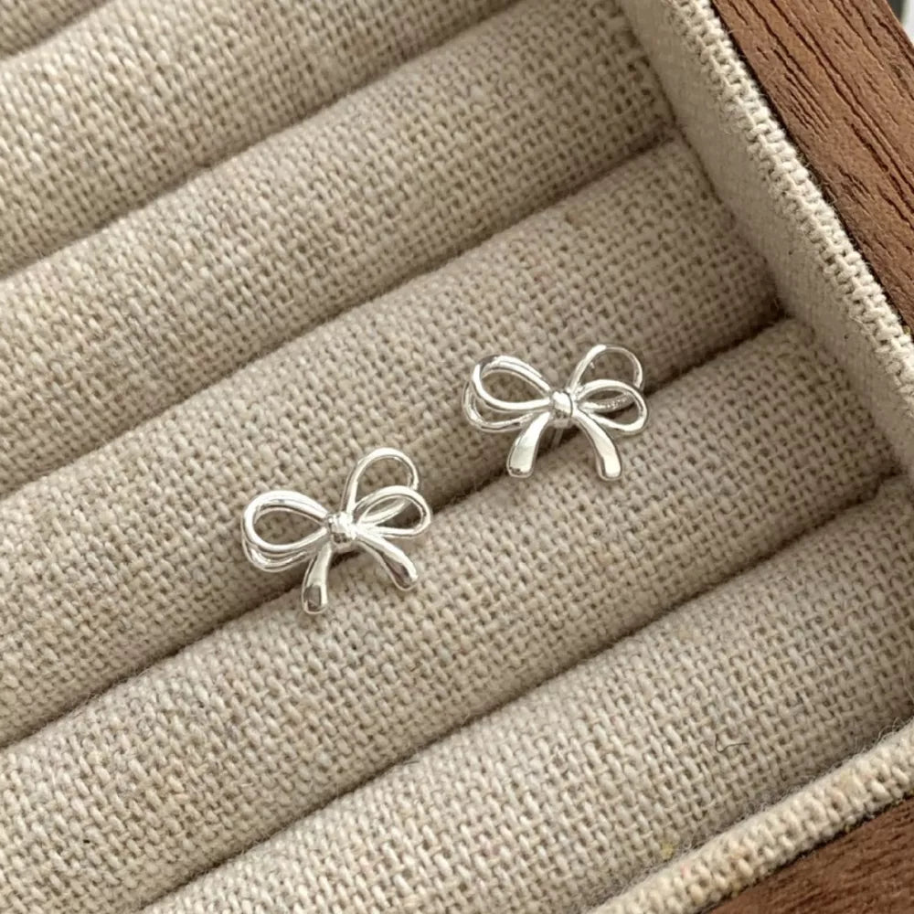earrings in silver featuring bow detail and fitted fit
