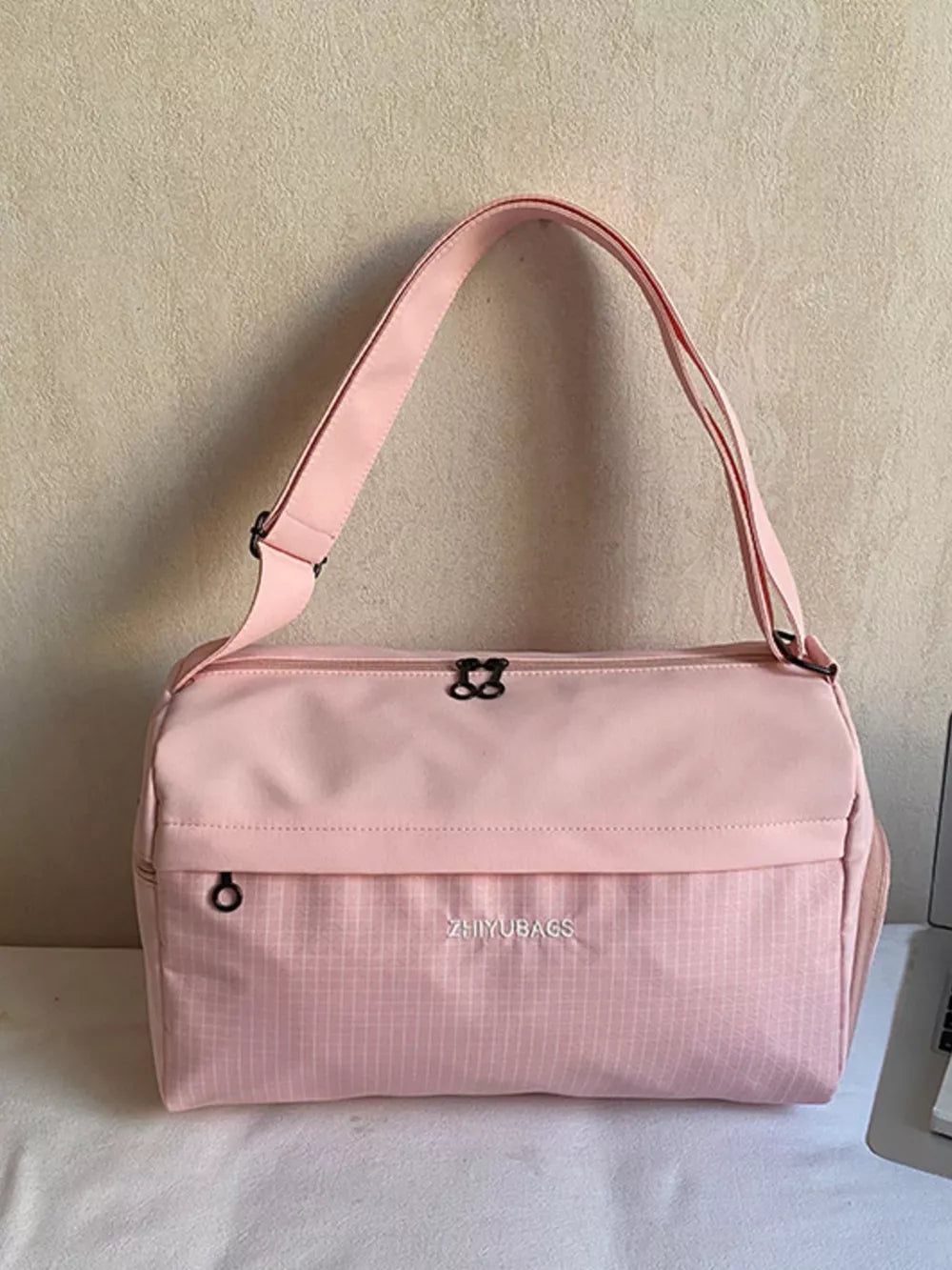 Pink travel organizer bag with plaid pattern and dual zippers.
