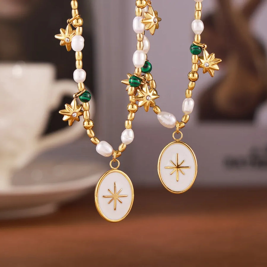 Gold celestial pendant necklace with pearls, starburst charms, and oval white enamel starburst pendants.