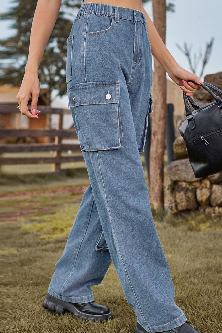 Relaxed wide leg denim cargo pants in light wash with utility pockets and button details.