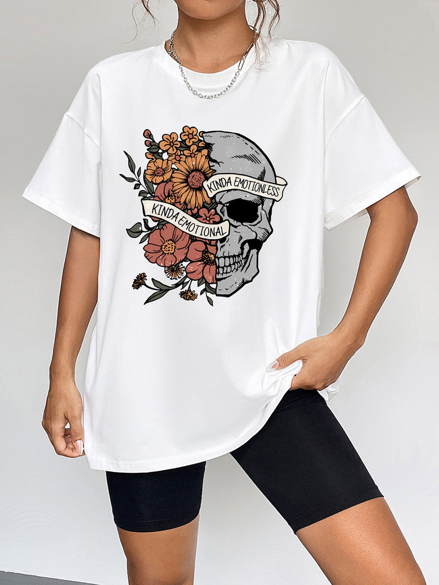 White oversized t-shirt with a skull graphic surrounded by flowers and text.