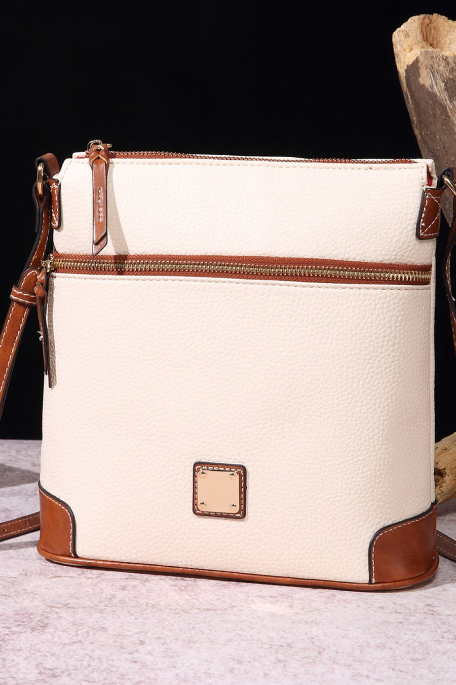 Ivory leather crossbody bag with brown trim and gold hardware.