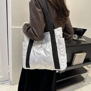 Padded nylon tote bag in silver with exterior pockets and black straps.