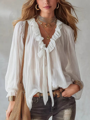 White frilled tie-front shirt with billowy sleeves and ruffled neckline.