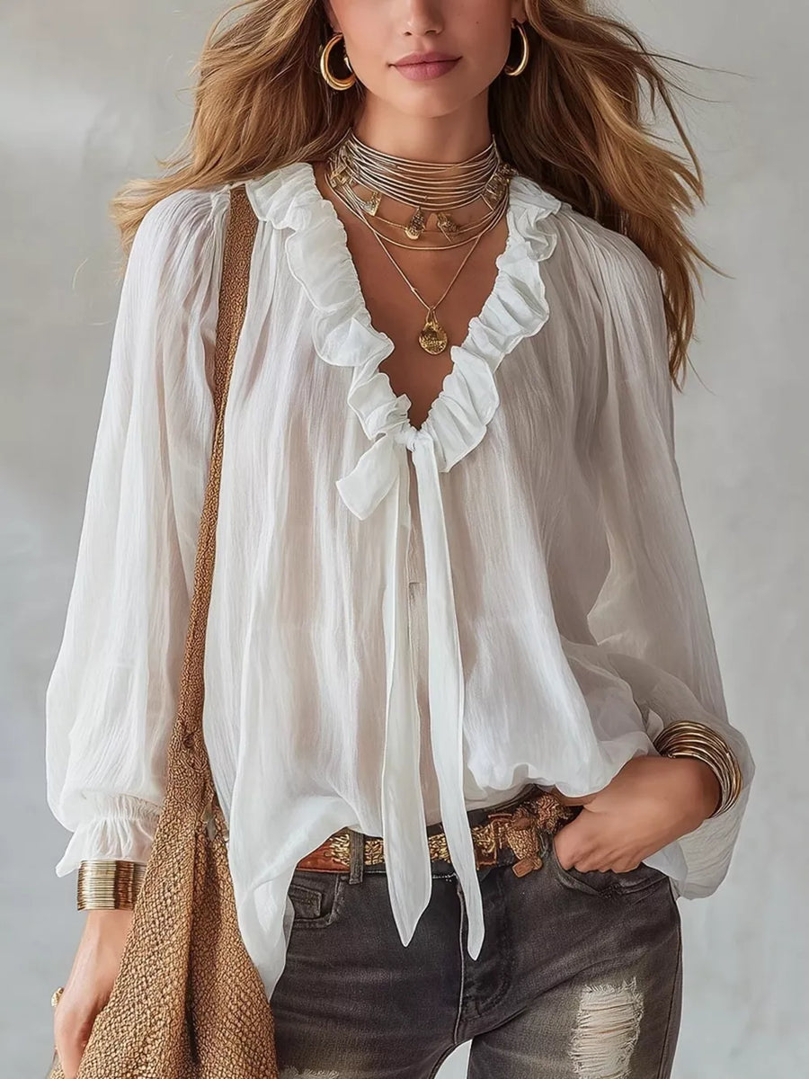 White frilled tie-front shirt with billowy sleeves and ruffled neckline.