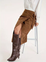Brown suede midi skirt with tie waist and high slit, styled with boots.