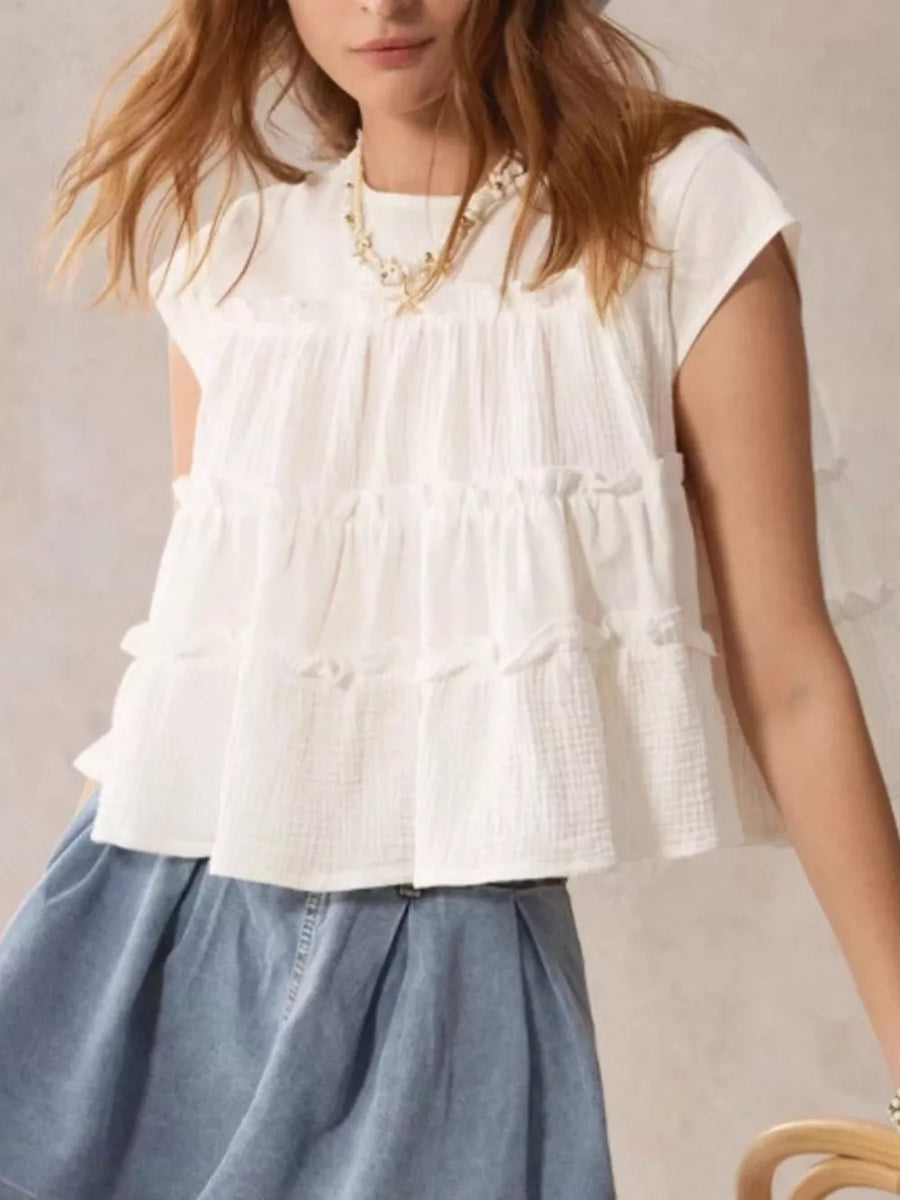 White tiered ruffle blouse with short sleeves and textured fabric.
