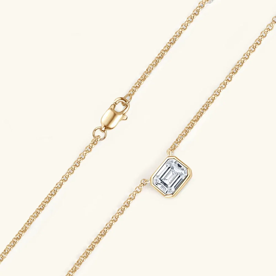 Gold necklace with emerald cut moissanite in bezel setting and lobster clasp.