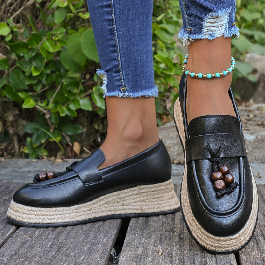 Black espadrille wedge slip-on loafers with braided jute sole and wood bead tassel detail.