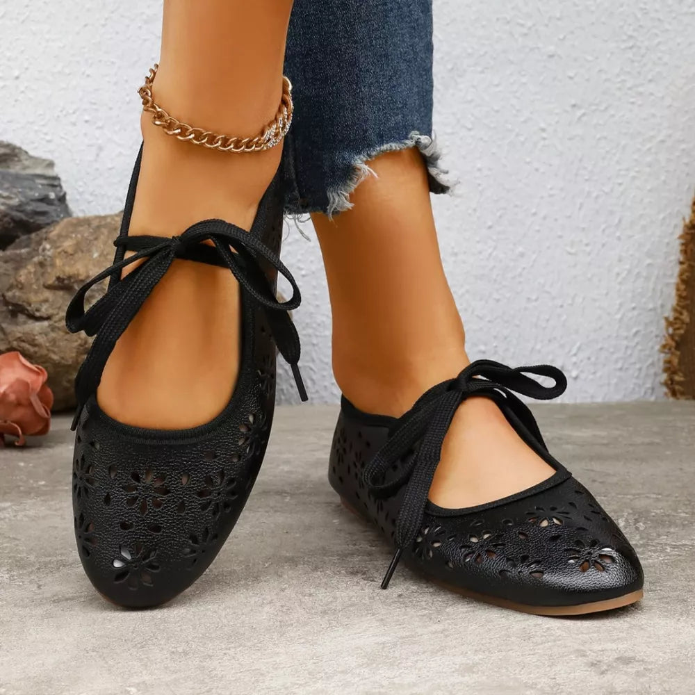 Black floral cutout slip-on flats with tie detail and ankle strap.
