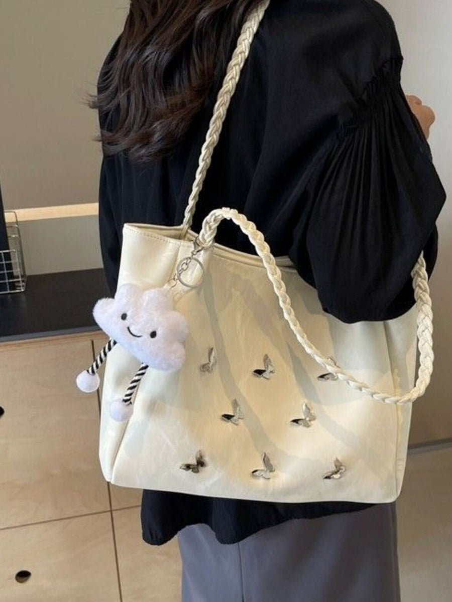 Cream shopper bag with braided handles, butterfly embroidery, and cloud charm.
