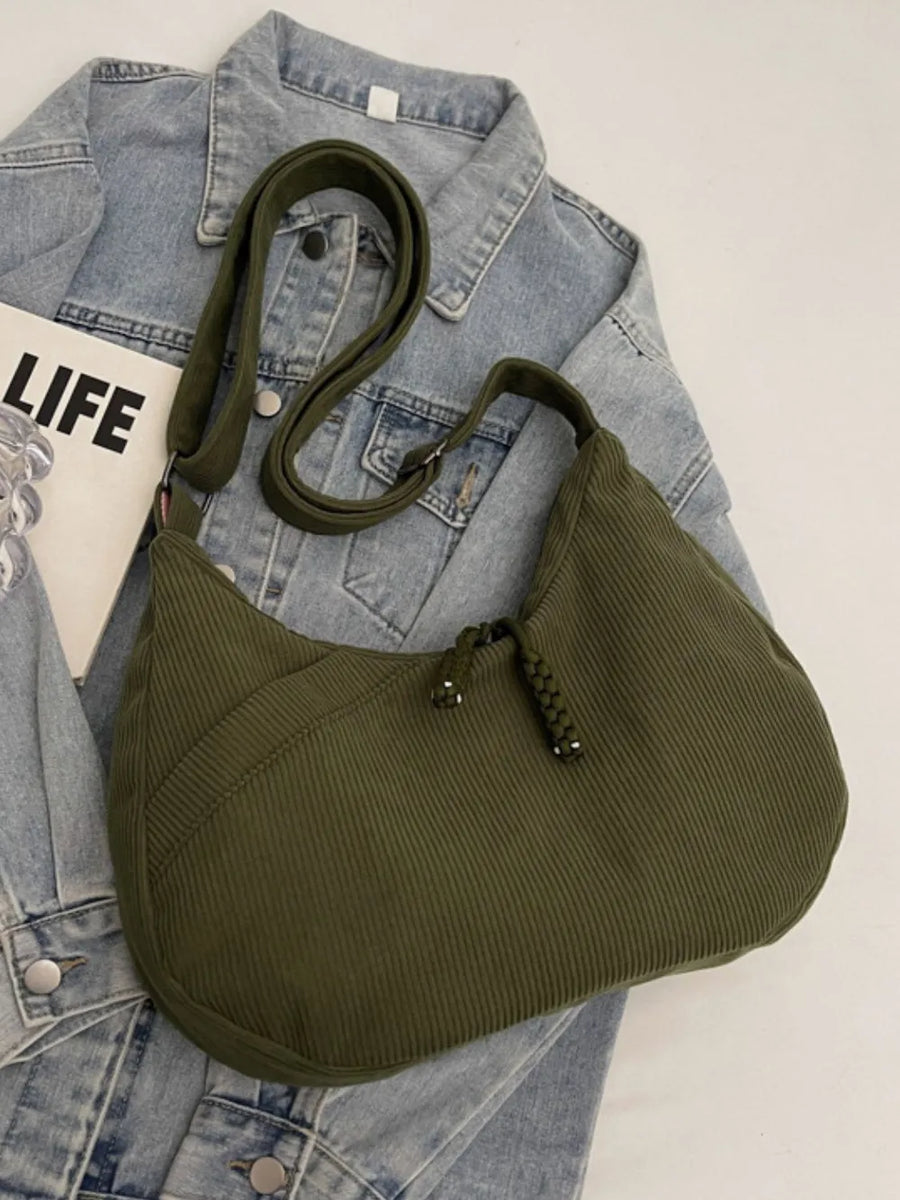 Moss green corduroy crescent shoulder bag with braided detail and adjustable strap.