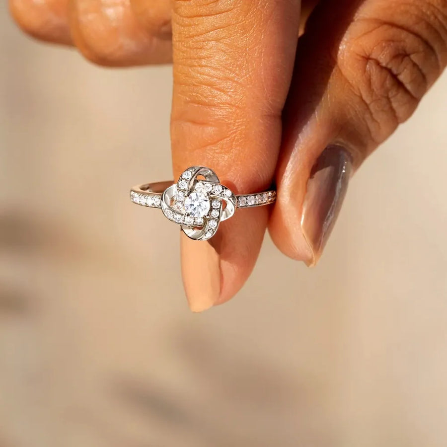 Silver ring with intertwined crystal knot design and pavé band.