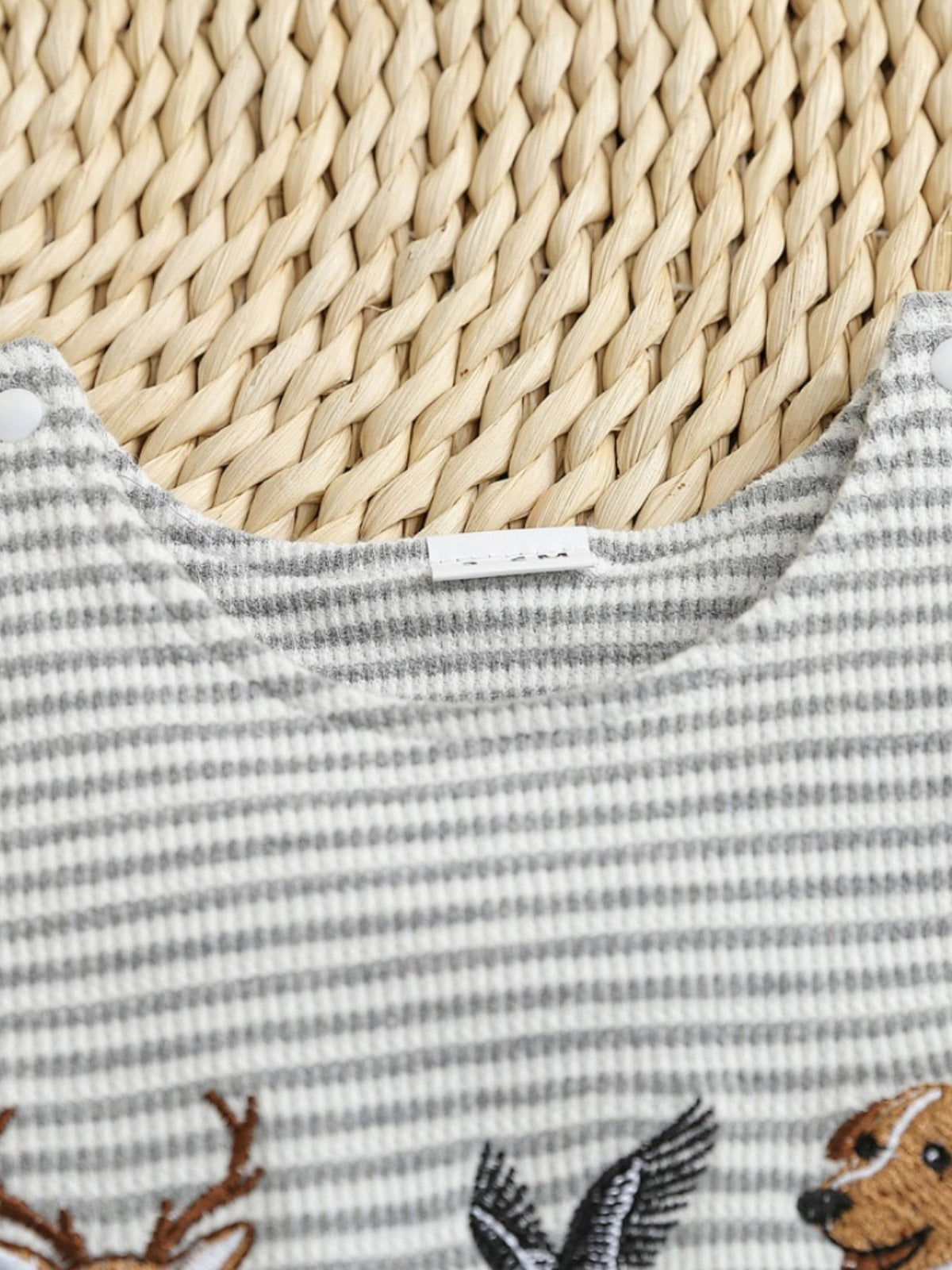 Baby one-piece with grey and white stripes and animal embroidery.