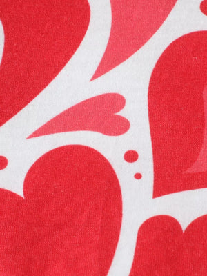 Baby polo shirt with red heart print on white cotton fabric.