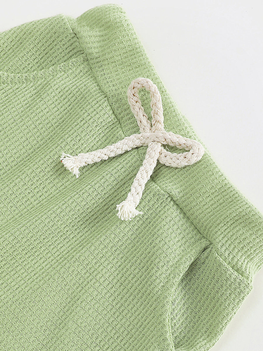 Green waffle knit children's pants with a decorative white drawstring bow.