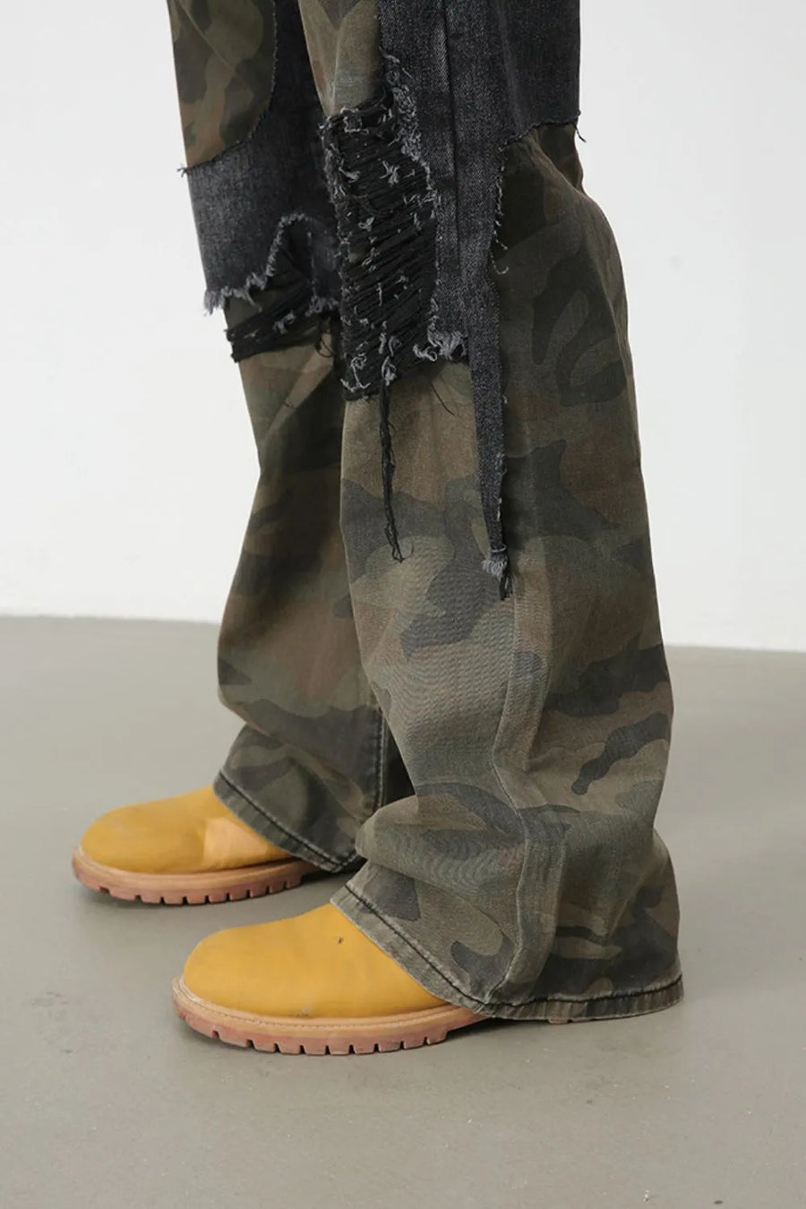 Distressed camo panel flare jeans with frayed denim patches and a wide leg.