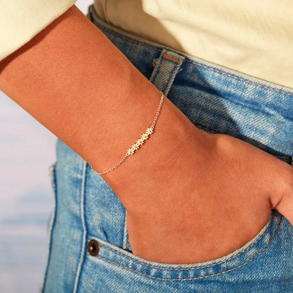 Silver daisy chain bracelet with delicate floral charms on a thin chain.