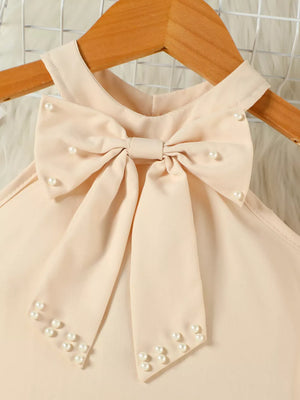 Beige toddler bowknot top with pearl accents and halter neck.