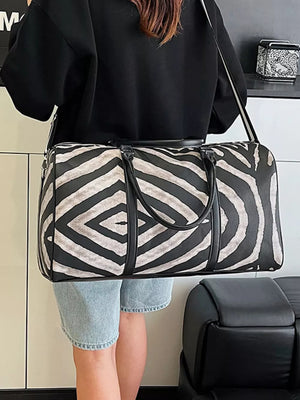 Large black and white zebra print duffle bag with carry handles and detachable strap.