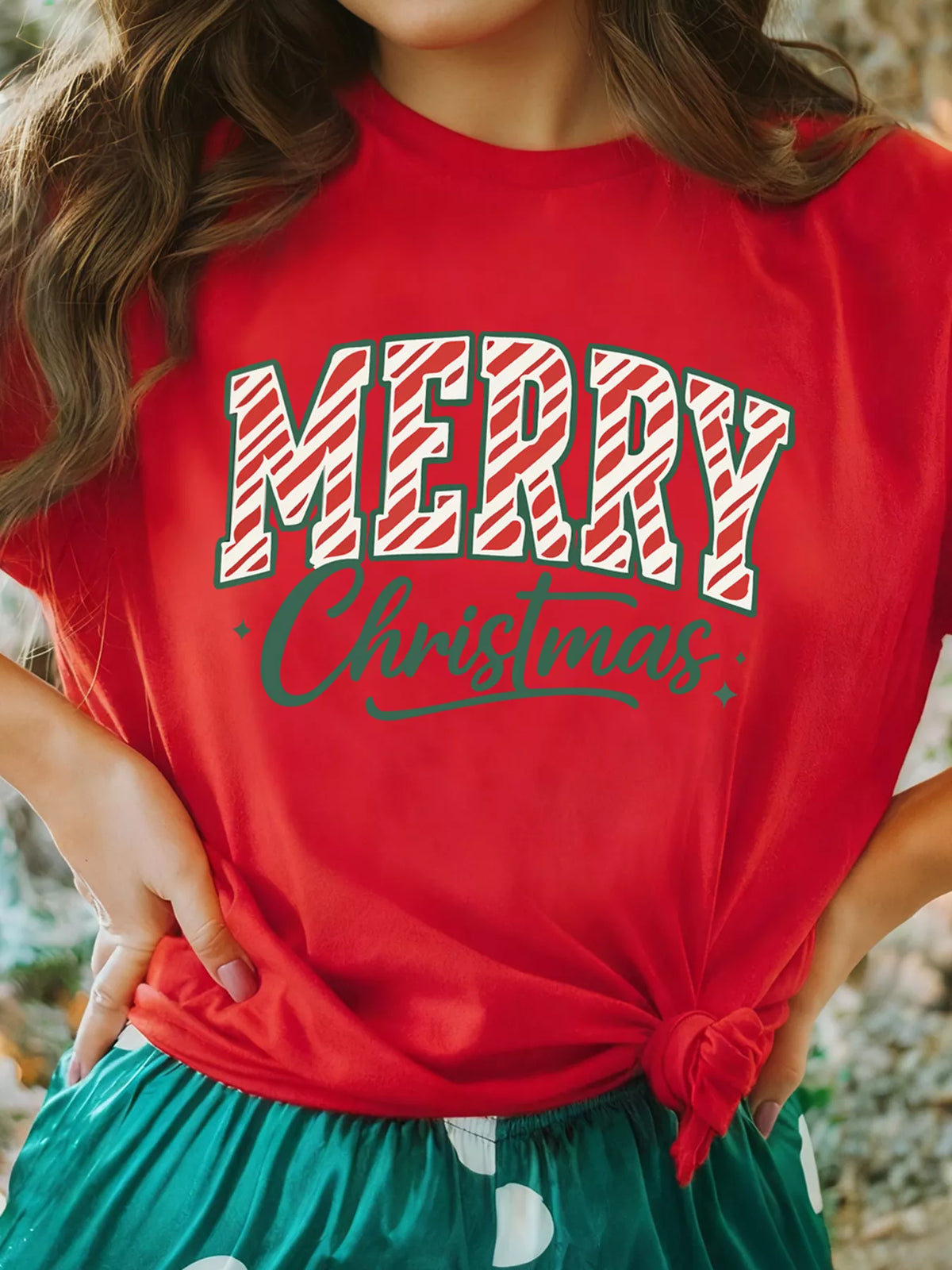 Red t-shirt with white and red striped Merry Christmas graphic and green script text.
