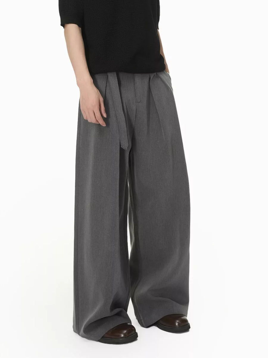 Grey wide-leg pleated sweatpants with a belted waist and a relaxed fit.