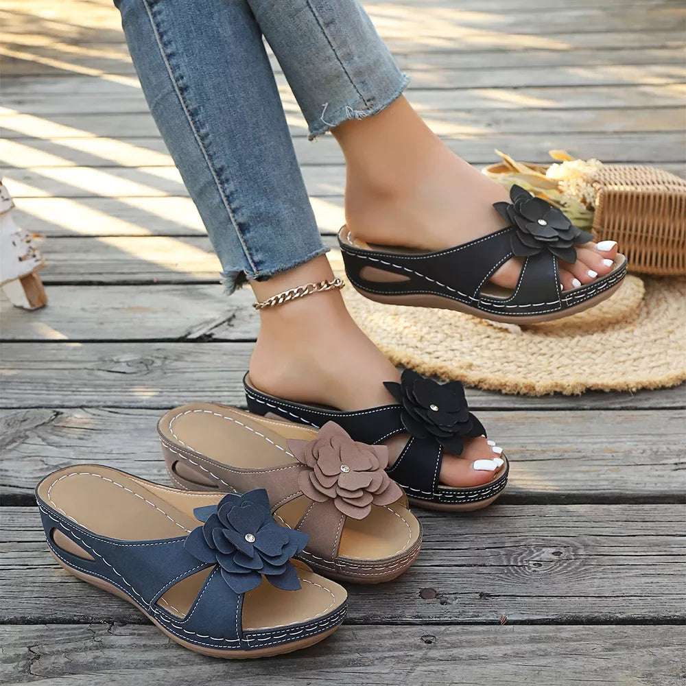 Floral embellished mid-wedge sandals in blue, brown, and black with open-toe design and comfortable fit.