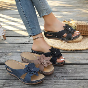 Floral embellished mid-wedge sandals in blue, brown, and black with open-toe design and comfortable fit.
